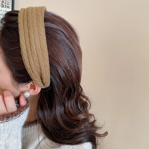 Détail d'un serre-tête en tricot marron avec motif torsadé porté par un mannequin