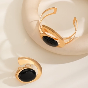 Detail of minimalist gold metal jewelry set with large oval black stone inlay