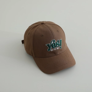 Close-up of brown cotton baseball cap featuring green 3D embroidery with YES text