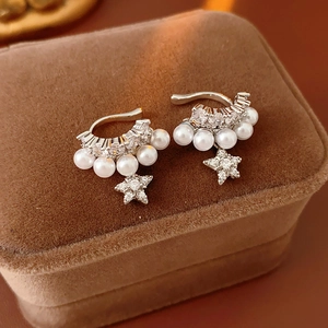 Macro shot of silver ear cuff with white pearls and zircon star pendant on velvet