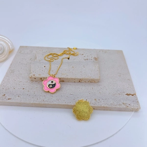 Detail view of pink enamel cherry blossom and Yin Yang pendant with gold textured flower