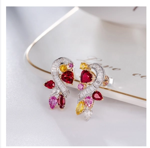Macro shot of heart-shaped earrings with colorful gemstones on white ceramic tray