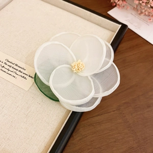 Close-up of elegant handmade white organza flower hair clip with yellow pistils