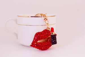 Detail von roten Strass-Lippen und Lippenstift-Schlüsselanhänger an einer Tasse