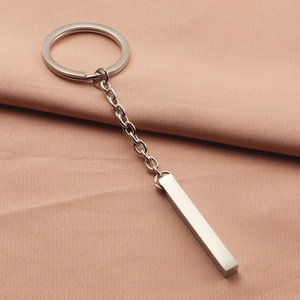 Polished rectangular stainless steel bar keychain on pink fabric, minimalist metal gift