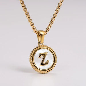 Macro view of gold round pendant with white shell inlay and 3D Z letter detail