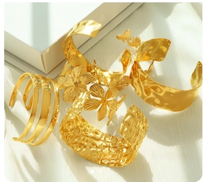 Close-up of golden titanium steel bracelets with hammered texture and floral details