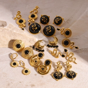 Detailed group shot of vintage gold earrings with black onyx on a textured stone surface