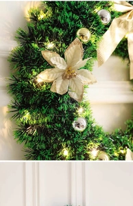 Detail of Christmas wreath with gold ornaments, white flower and warm LED lights