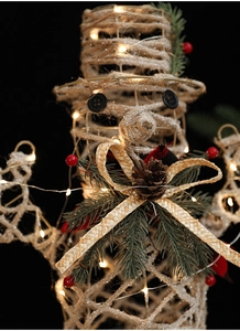 Close-up of champagne-colored snowman Christmas ornament with warm LED lights and pine cones