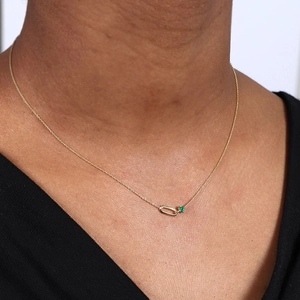 Detail of S925 silver paperclip necklace with green emerald gemstone on a female model