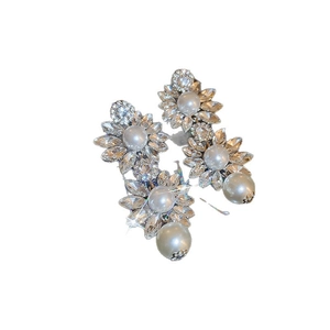 Boucles d'oreilles fleurs élégantes avec strass brillants et perles sur fond blanc pur