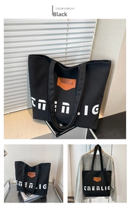 Detailed view of black canvas tote bag with contrast lettering and brown leather patch