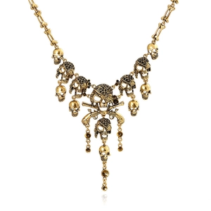 Vintage gold skull and pistol necklace with black gem eyes on white background
