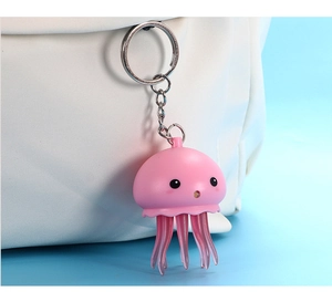 Porte-clés méduse rose avec tentacules accroché à un sac en toile sur fond bleu