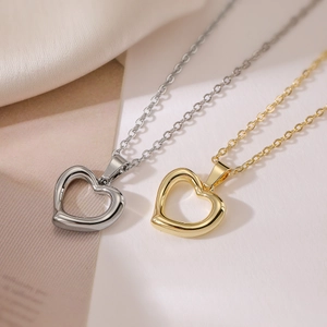 Minimalist hollow heart pendant necklaces in gold and silver finishes on a dual-tone background
