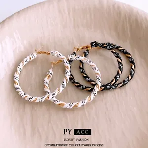 Golden hoop earrings wrapped in black and white leather with NICE printed pattern