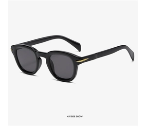 Detail view of black square sunglasses with dark lenses and golden arrow accents
