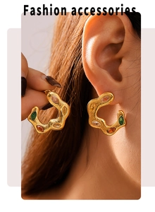 Detail of gold twisted C-shape earrings with colorful marquise-cut zircon stones