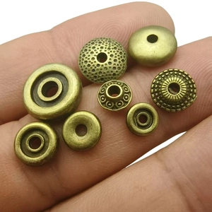 Antique bronze wheel spacer beads for DIY jewelry making held in hand on white background
