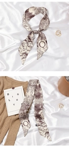 Detail of silk ribbon scarf with Q-letter print styled on a brown knit sweater