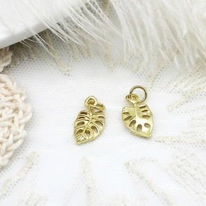 Makroaufnahme von zwei goldenen Monstera-Blattanhängern für DIY-Schmuck auf Spitze