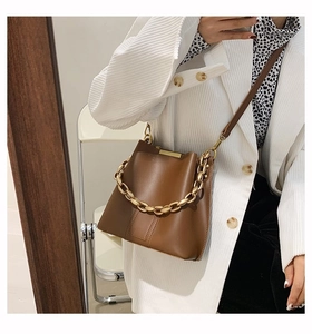 Brown leather bucket bag with chunky chain detail shown in a stylish mirror selfie