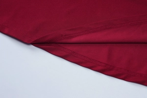 Macro shot of dark red knit dress hemline showing detailed double-needle stitching quality