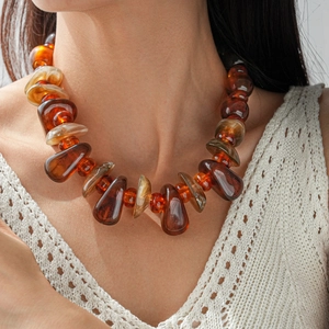 Détail de perles d'acrylique ambrées irrégulières sur un long collier bohème