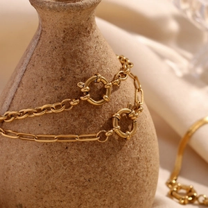 Bracelets à maillons trombone et ronds en acier doré avec fermoir à ressort sur vase