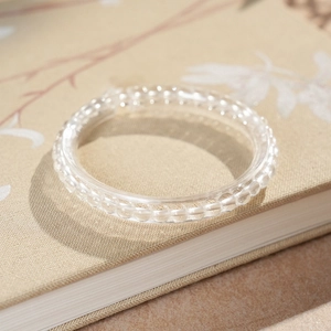Macro detail of clear crystal beaded bracelet on vintage floral book, elegant jewelry texture