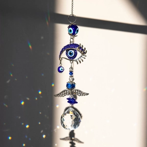 Blue Evil Eye suncatcher with metal angel wings and faceted crystal ball reflecting rainbows