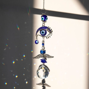 Blue Evil Eye suncatcher with metal angel wings and faceted crystal ball reflecting rainbows
