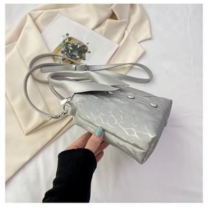 Detailed macro of silver metallic wrinkled texture bag with chrome rivets and chain