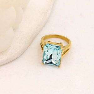 Dettaglio dell'anello con gemma blu taglio smeraldo e fascia dorata su bianco