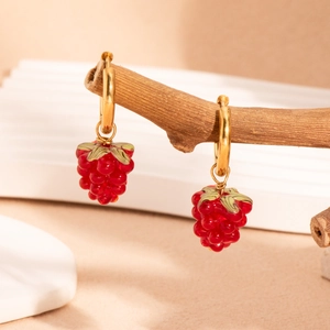 Créoles dorées chic avec pendentifs framboises rouges suspendues à une branche en bois