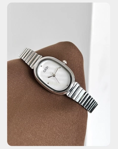 Macro shot of an oval silver steel watch featuring a white mother of pearl dial finish