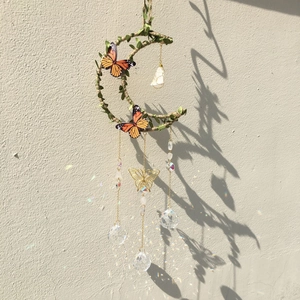 Detail of moon-shaped wind chime with butterflies and crystal balls casting rainbow light