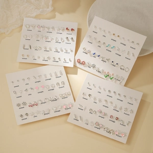 Ensemble de boucles d'oreilles argentées avec perles et strass sur tissu blanc