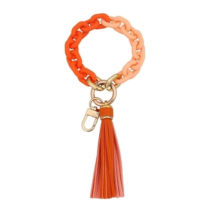 Detail of orange gradient acrylic link keychain with golden clasp and leather tassel
