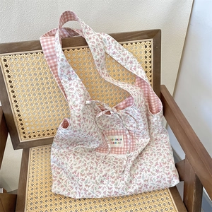 Close-up of floral canvas tote bag with pink gingham pocket on a vintage wooden chair