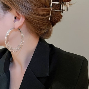 Detail view of stylish multi-layer silver hoop earrings worn by a female model