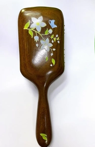 Detailed close-up of sandalwood massage comb featuring elegant floral and butterfly motifs