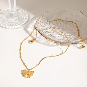 Detailed close-up of a golden bowknot pendant necklace with delicate beaded chain link