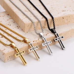 Four stainless steel Jesus cross necklaces in gold, silver and black displayed on stone