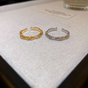 Detailed close-up of gold and silver bamboo-style rings with zircon stones on white surface
