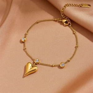 Detail of 18K gold stainless steel heart bracelet with three sparkling zircons on satin