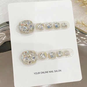 Faux ongles d'orteils argentés pailletés faits main avec strass sur carte de présentation