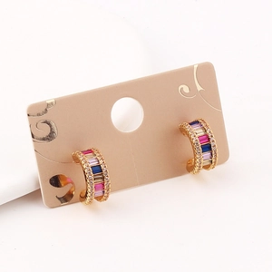 Detailed view of C-shaped gold earrings featuring micro-pave rainbow cubic zirconia