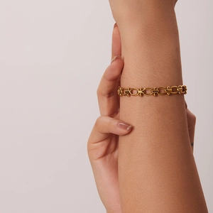 Detail of gold titanium steel bracelet with green zircon inlay worn on the wrist